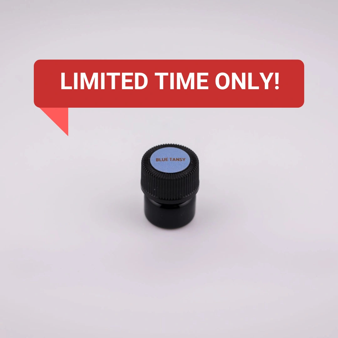 Black bottle with blue label of Blue Tansy essential oil on a white background.